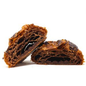 Buttery, flaky chocolate croissant dough encasing two rich, dark chocolate batons. A classic French pastry, baked to perfection.