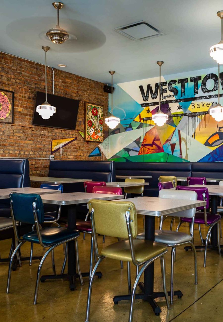 Bright and inviting interior of West Town Bakery & Diner with colorful mural, diner-style seating, and exposed brick walls.